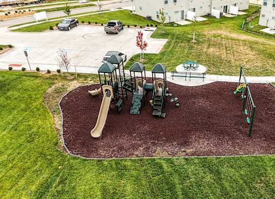 A playground with a slide, swings, and a seesaw.