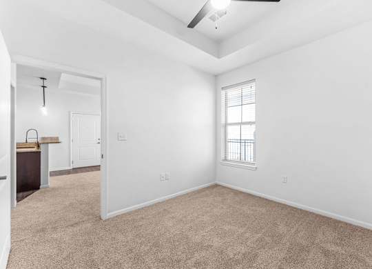 A room with a ceiling fan and a window with blinds.
