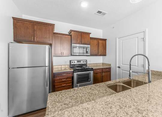 A kitchen with a stainless steel refrigerator, microwave, oven, and sink.