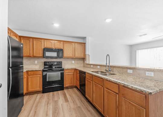 A kitchen with wooden cabinets and black appliances.