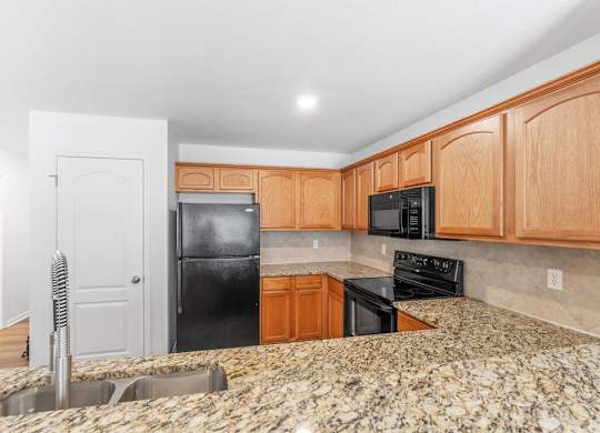 A kitchen with granite countertops and wooden cabinets.