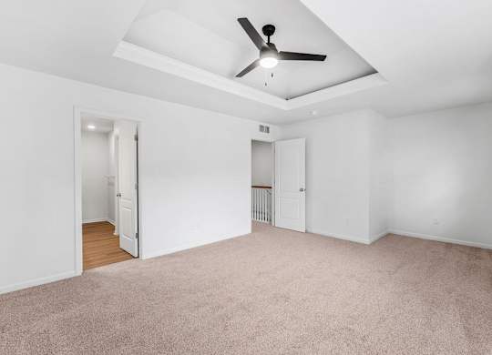 A room with a ceiling fan and carpeted floor.
