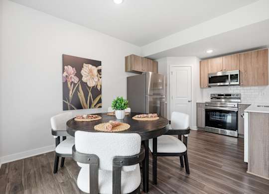 A dining room with a table set for two and a kitchen in the background.