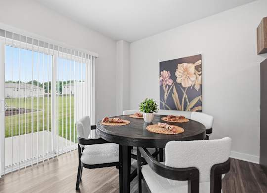 A dining room with a table set for two and a view of a parking lot outside.