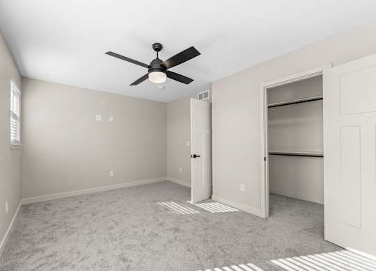 A room with a ceiling fan and a carpeted floor.