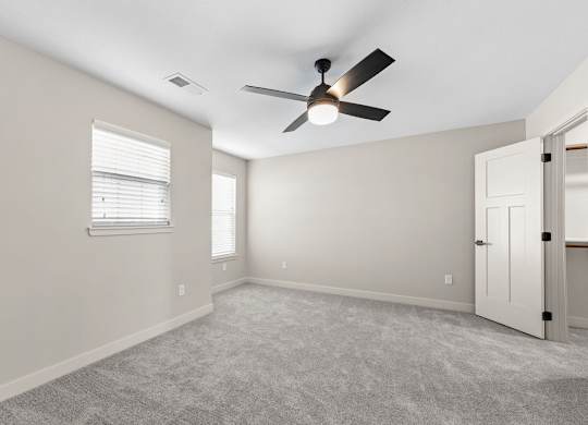 A room with a ceiling fan and a carpeted floor.