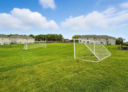 A soccer field with two goal nets and a building in the background.