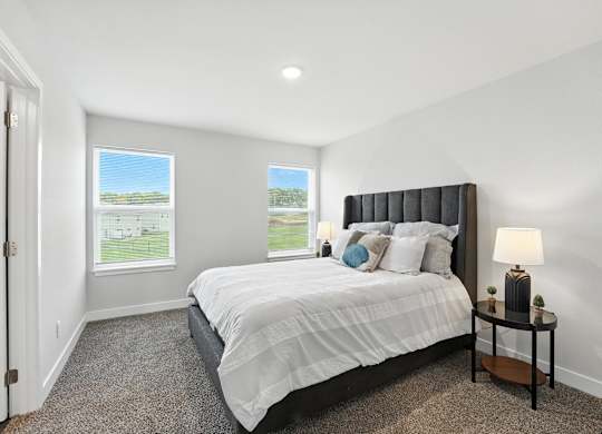 A bedroom with a large bed and a window overlooking a green field.