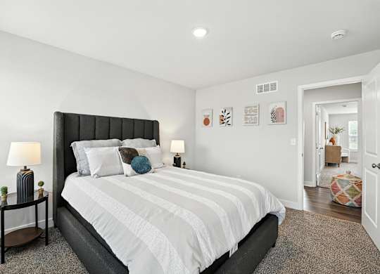 A bedroom with a large bed and a nightstand with a lamp.