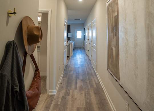 A long hallway with a coat and hat hanging on the wall.