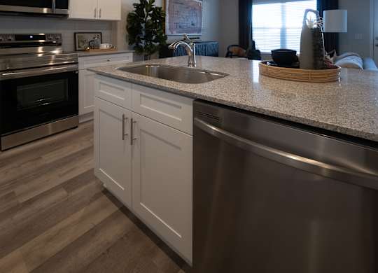 A modern kitchen with a stainless steel sink and wooden flooring.