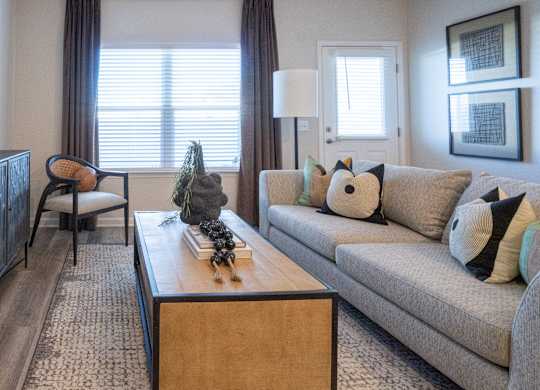 A living room with a grey couch, a wooden coffee table, and a painting on the wall.