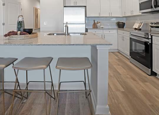 A kitchen with a white countertop and two stools.
