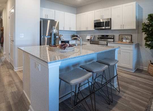 A kitchen with a white island and bar stools.