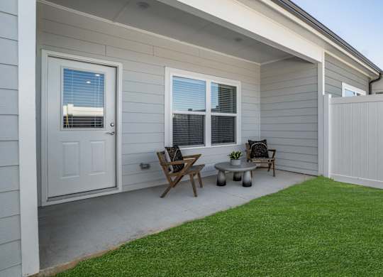 A small patio with a table and chairs outside a house.
