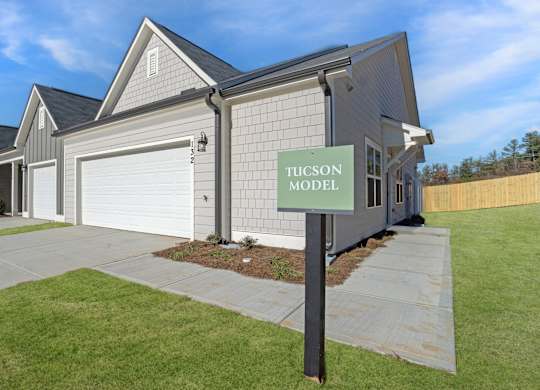 A Tucson model house sign is displayed in front of a modern house.
