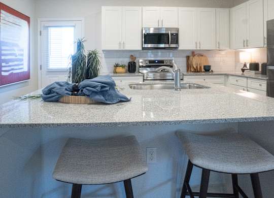 A kitchen with a white countertop and two stools.