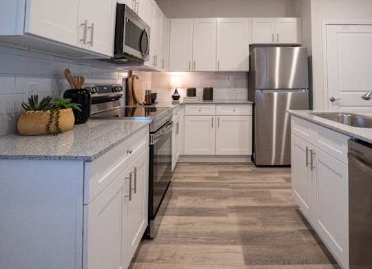 A kitchen with white cabinets and a stainless steel refrigerator.