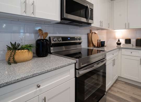 A kitchen with a black stove top oven and white cabinets.