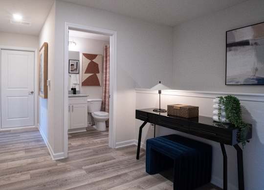 A hallway with a bench and a lamp on a desk.
