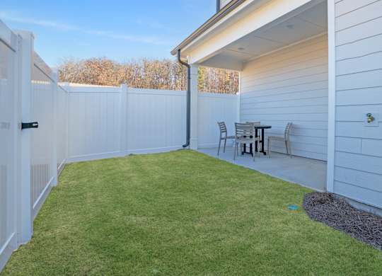 A backyard with a white fence and a small table and chairs.
