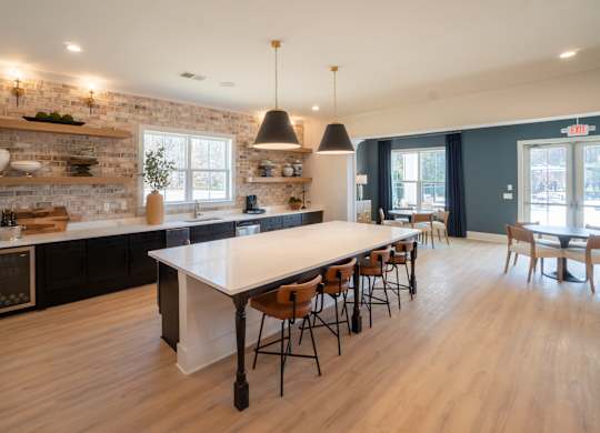 A kitchen with a long table and chairs.
