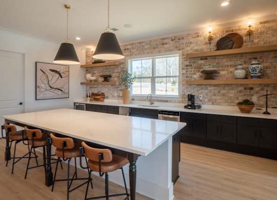 A kitchen with a white island and black chairs.