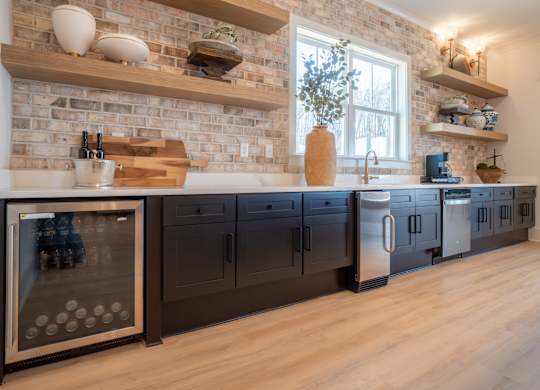 A kitchen with a brick wall and wooden floors.