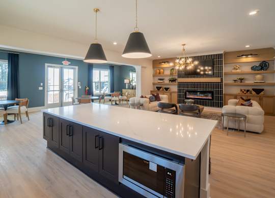 A modern kitchen with a large island and a fireplace in the background.