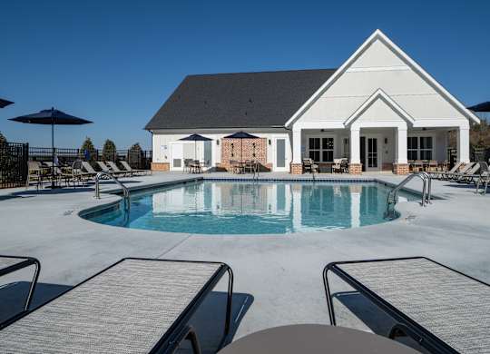 A pool with a house in the background.