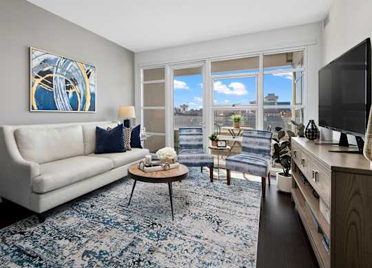 a living room with a white couch and a blue rug   and a window