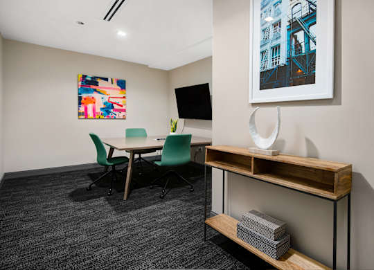 A conference room with a table, chairs, and a painting on the wall.