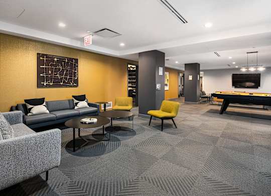 A room with a grey carpet and a grey sofa.