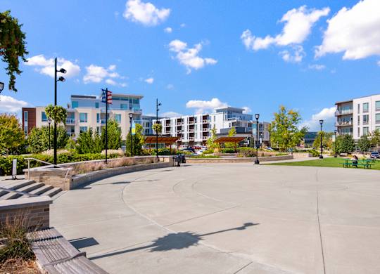 A large open plaza with a flagpole and apartment buildings in the background.