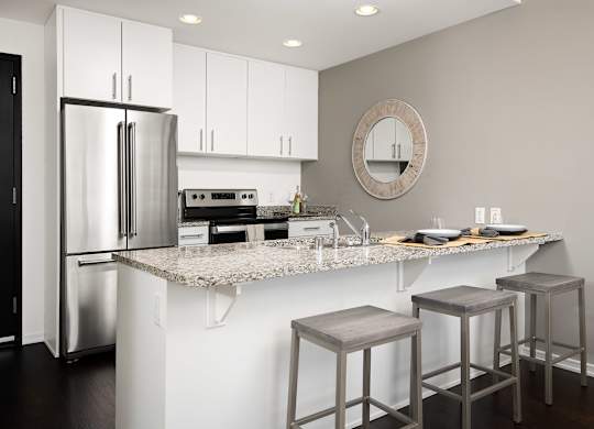 a kitchen with white cabinets and a counter top with three stools