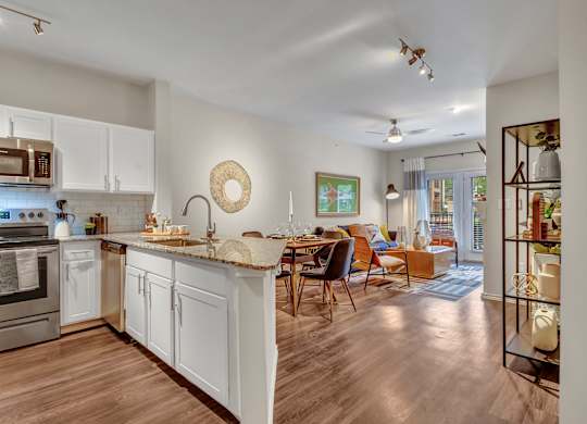A modern kitchen with white cabinets and a wooden floor.