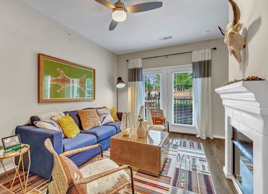 A living room with a blue couch and a painting of a giraffe on the wall.