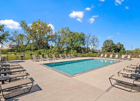 A pool surrounded by lounge chairs on a sunny day.