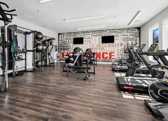 A gym with a variety of equipment including treadmills, weights, and exercise machines.