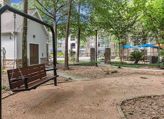 A swing set in a playground with a white building in the background.