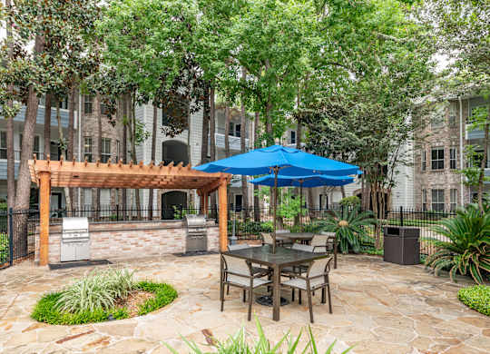 A patio with a table and chairs under a blue umbrella.