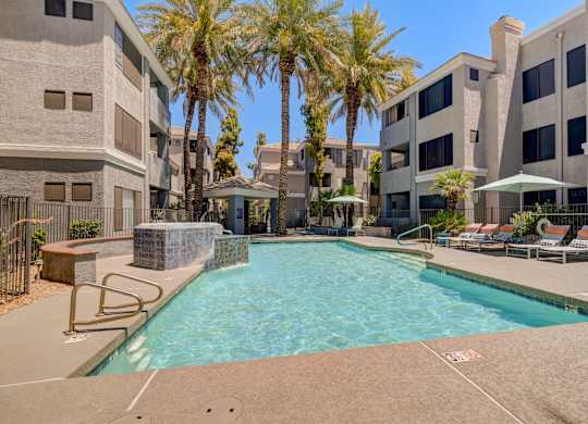 A swimming pool surrounded by palm trees and lounge chairs.