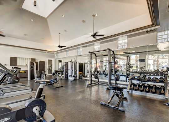 A spacious gym with a variety of equipment including treadmills, weight machines, and free weights.
