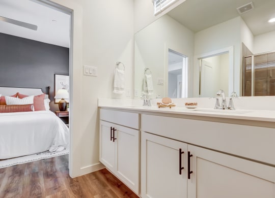 a bathroom with white cabinets and a large mirror with dual sink vanity
