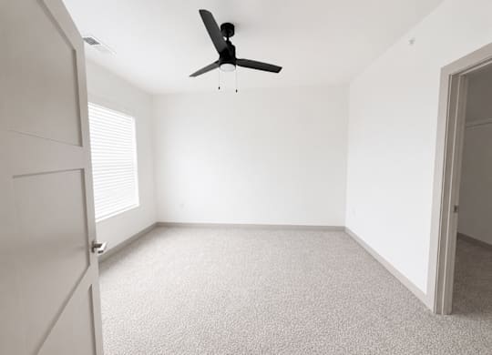 A room with a ceiling fan and carpeted floor.