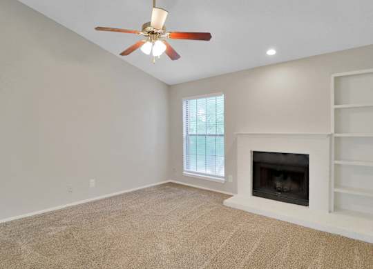 A room with a ceiling fan and a fireplace.