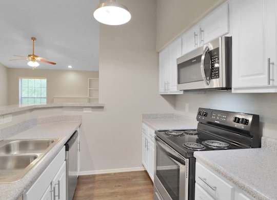 A kitchen with a stove, microwave, and oven.