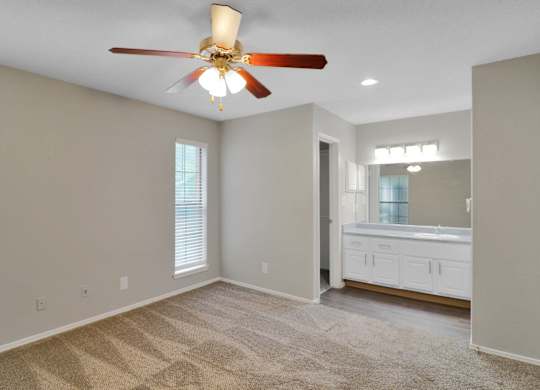 A room with a ceiling fan and carpeted floor.