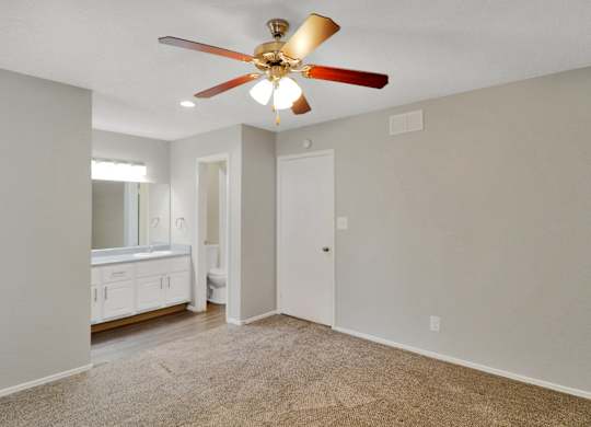 A room with a ceiling fan and carpeted floor.
