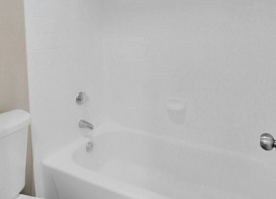 A white toilet sits next to a white bathtub.